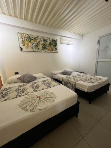two beds in a hotel room with a painting on the wall at Hotel Boutique Santa Ana in Cartago