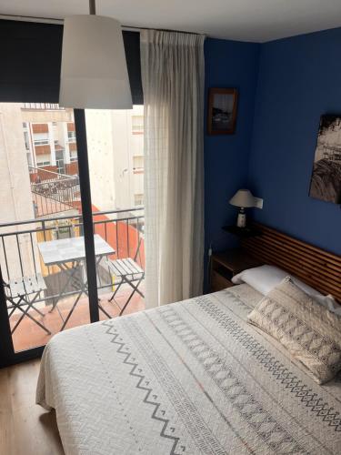 a bedroom with a bed with a blue wall and a balcony at Hostal La Lluna in Arenys de Mar