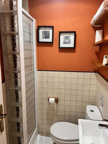 a bathroom with a toilet and an orange wall at Hostal La Lluna in Arenys de Mar
