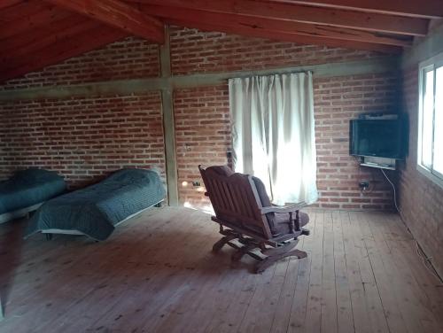 a room with a rocking chair and a bed and a window at Casa y Departamento en Centenario in Centenario