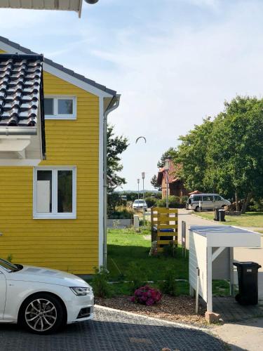 a white car parked in front of a yellow house at Ferienhaus Traumspot in Wiek auf Rügen