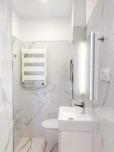 a white bathroom with a toilet and a sink at Fuentes de luz in San Sebastián de los Reyes