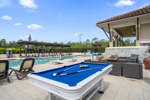 a pool table on a patio next to a swimming pool at Sunny Summer Awaits - Renovated Townhome by Disney! in Orlando