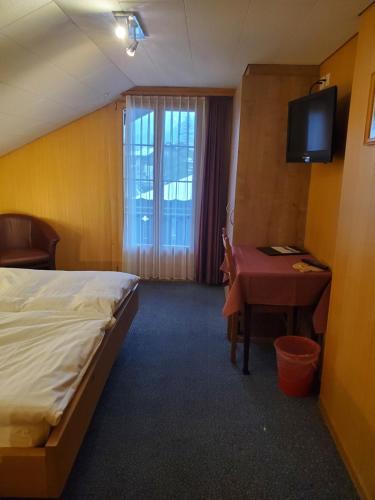 a hotel room with a bed and a desk and a television at Hotel Garni Alpenruh in Lenk