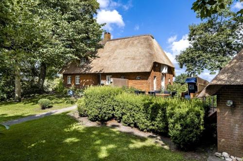 ein altes Backsteinhaus mit Strohdach in der Unterkunft Ferienhaus Katzhörn in Emmelsbüll-Horsbüll