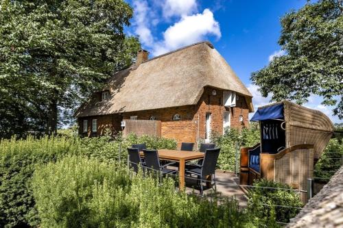 ein Haus mit einem Tisch und Stühlen davor in der Unterkunft Ferienhaus Katzhörn in Emmelsbüll-Horsbüll