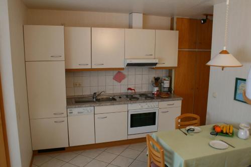 una cucina con armadi bianchi e un tavolo con tavolo. di Sternenhimmel a Klausdorf