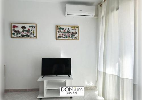 un salon avec une télévision à écran plat sur un mur blanc dans l'établissement DOMuum Holidays - AUGUSTA Family Home, à Salou