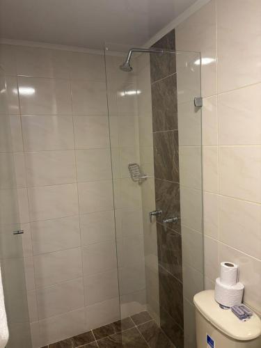 a bathroom with a glass shower with a toilet at Hotel Balcones del Estadio in Medellín