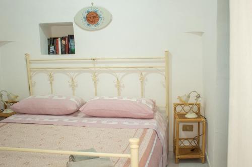 a bedroom with a bed with pink pillows and a clock at Trullo Fortuna in Cisternino