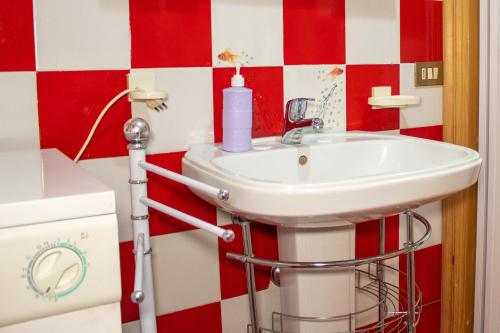 a bathroom with a sink and red and white checkered wall at Trullo Fortuna in Cisternino