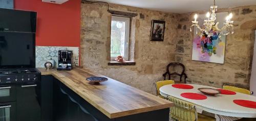- une cuisine avec un comptoir en bois et une table dans l'établissement Moulin de Saint Gely, à Salvagnac-Saint-Loup