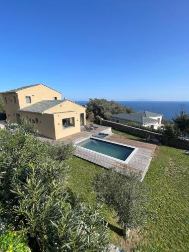 une maison avec une piscine à côté de l'océan dans l'établissement Magnifique Villa Neuve Cap Corse, à Brando