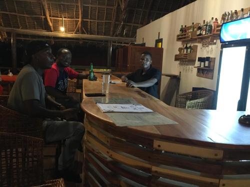 a group of men sitting around a large wooden bar at Sand and Sunset in Kendwa