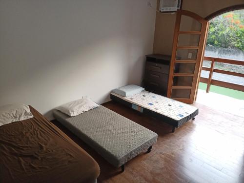 a room with two beds and a book shelf at Arrasta Hostel quarto compartilhado 2 in São Sebastião