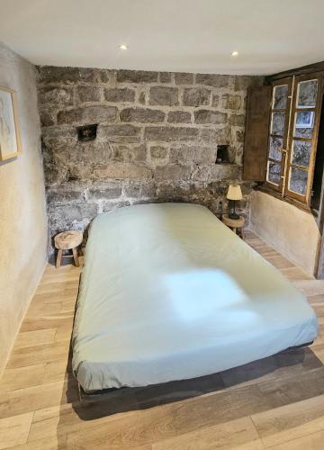 un grand lit dans une pièce avec un mur de briques dans l'établissement Appartement vue imprenable montagne, à Serra-di-Scopamene