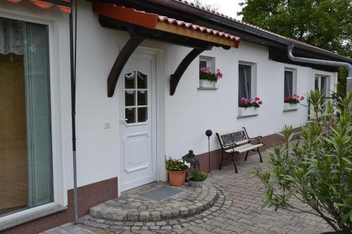 a white house with a door and a bench at Bärenfalle in Neuhardenberg