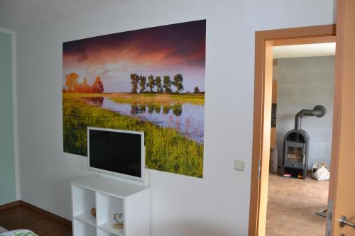 a living room with a tv and a painting on the wall at Bärenfalle in Neuhardenberg
