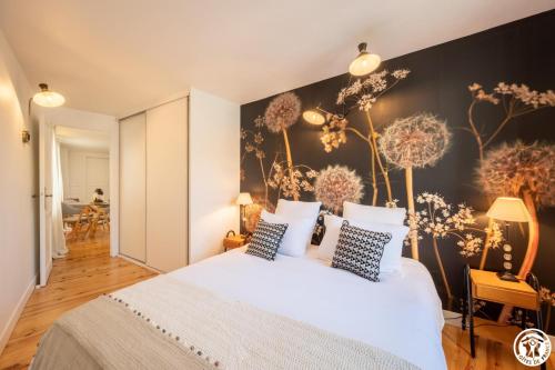 a bedroom with a large white bed and a wall with dandelions at L'appart in Compiègne