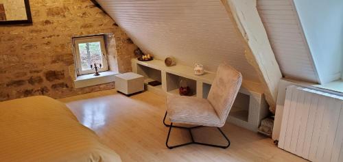 une chambre avec un lit et une chaise dans une pièce dans l'établissement Moulin de Saint Gely, à Salvagnac-Saint-Loup