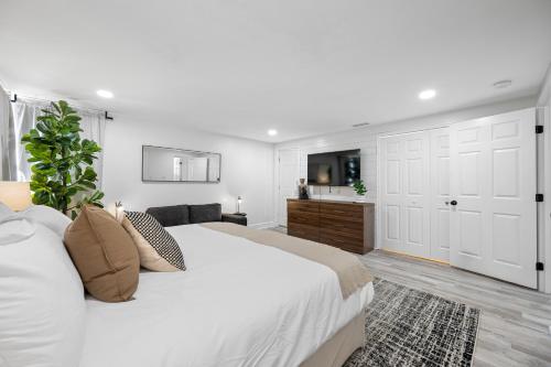 a white bedroom with a large bed and a bathroom at The Perfect Family Retreat w Pool and Games in West Chase