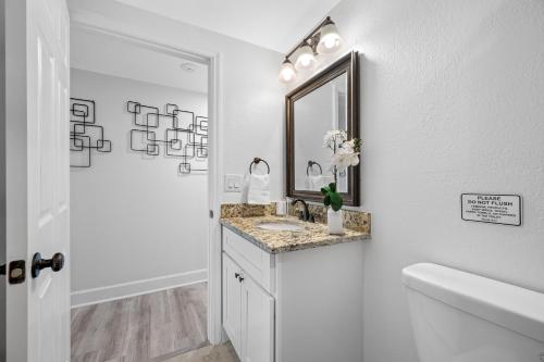 a white bathroom with a sink and a mirror at The Perfect Family Retreat w Pool and Games in West Chase