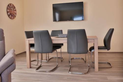a table with four chairs and a television on a wall at Wohnung "Greifswald" in Gützkow