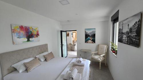 a white bedroom with a large bed and a chair at Apartment Stari Pazar 2 in Konjic