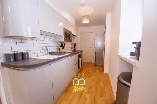 a kitchen with white cabinets and a wooden floor at Affleck Stay 2 - SJA Stays - Modern 2 Bed Apartment in Aberdeen