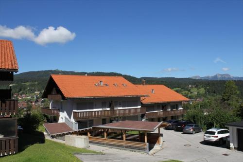 a building with an orange roof with a parking lot at Appartement Raineck in Mittenwald