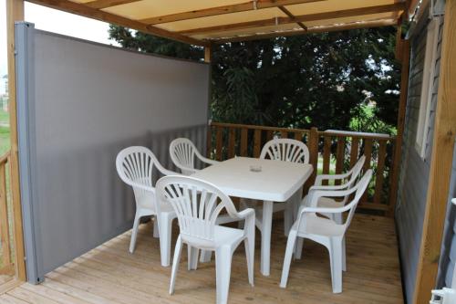 une table et des chaises blanches sur une terrasse en bois dans l'établissement Mobile Home 6 personnes climatisé, à Port-la-Nouvelle