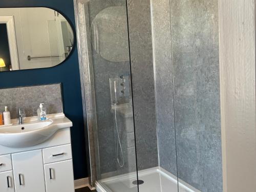 a shower with a glass door next to a sink at The Victoria Inn in Haddington