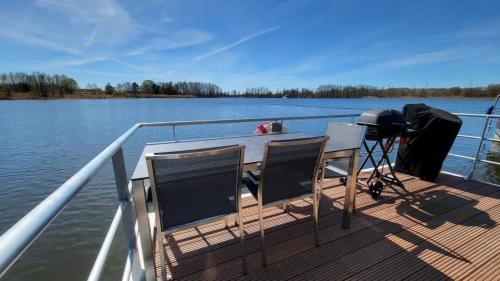 a boat with a table and chairs on the deck at Hausboot Red Pearl in Zehdenick