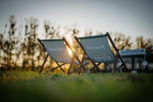 two lawn chairs sitting in the grass in the sun at Hausboot Red Pearl in Zehdenick