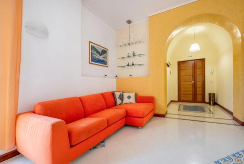 an orange couch in a living room with a door at Marziale Luxury Apartment in Sorrento