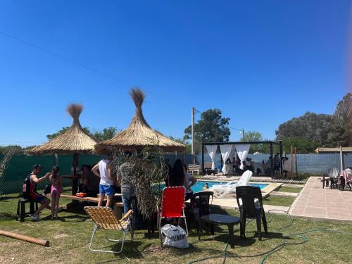 a group of people standing under umbrellas near a pool at Quinta La Deseada Brandsen in Estación Coronel Brandsen