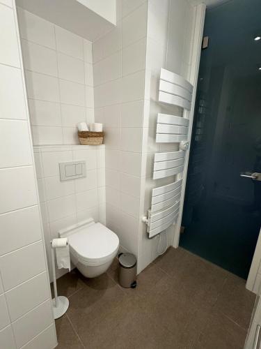 - une salle de bains blanche pourvue de toilettes et d'un panier de serviettes dans l'établissement Un havre de paix, face mer, à Wimereux