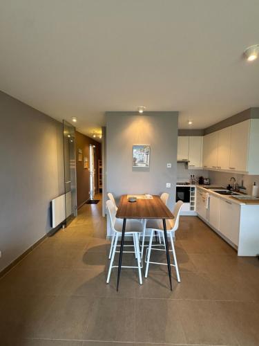 - une cuisine avec une table en bois et des chaises blanches dans l'établissement Un havre de paix, face mer, à Wimereux
