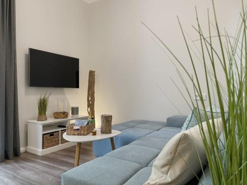 a living room with a blue couch and a tv at Ferienwohnung Kleine Auszeit in Neuhaus