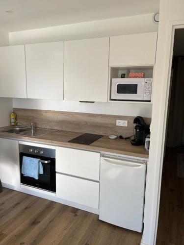 une cuisine avec des armoires blanches et un micro-ondes dans l'établissement Studio 4 people Stella beach, à Cucq