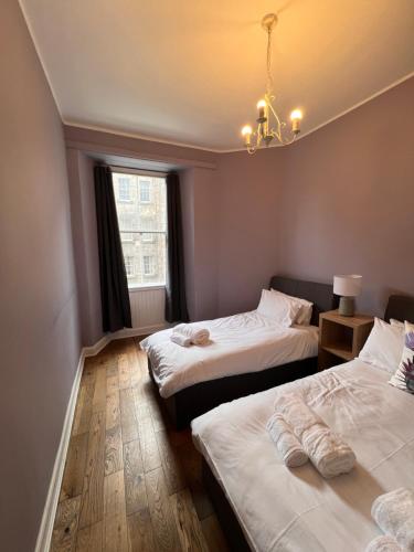 une chambre avec deux lits et un lustre dans l'établissement John Knox's Apartment on Edinburgh's Royal Mile, à Édimbourg