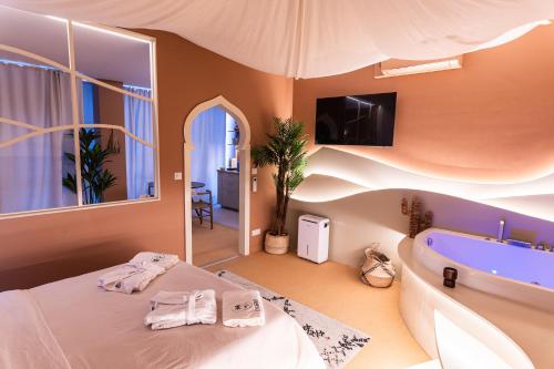 - une chambre avec une baignoire et un lit avec des serviettes dans l'établissement L'OASINA - Spa privé - Voyagez dans le Désert, à Bourg-en-Bresse