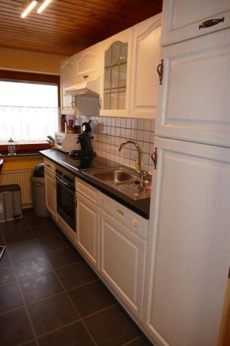 a kitchen with white cabinets and a sink at FeWo Bergenrot Urlaub mit Hund in Arnsberg