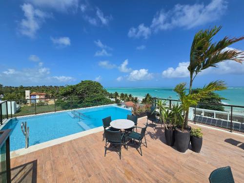 eine Terrasse mit Tisch und Stühlen neben einem Swimmingpool in der Unterkunft Apto Praia Barra Grande, Camurim Residence in Maragogi