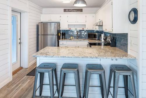 a kitchen with a counter with stools around it at Coastal Condos on the Marsh 5A in Dauphin Island