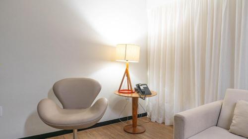 a room with a chair and a lamp and a phone at Pontes Home Stay - Flats em Boa Viagem por Yolo in Recife