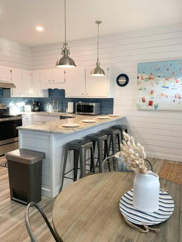 a kitchen with a counter with stools and a table at Coastal Condos on the Marsh 6A in Dauphin Island