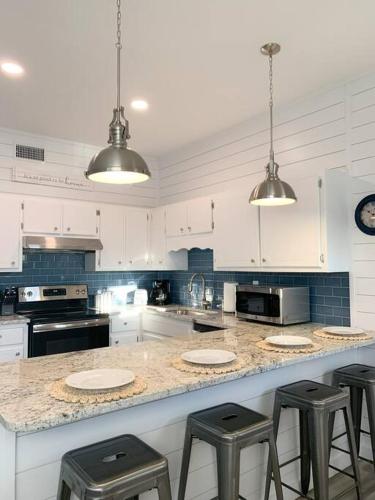 a kitchen with white cabinets and a counter with stools at Coastal Condos on the Marsh 6A in Dauphin Island