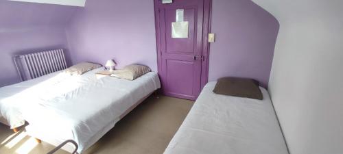 Cette chambre comprend 2 lits et une porte violette. dans l'établissement Le bouf tard chambre vue sur jardin CH7, à Vendôme
