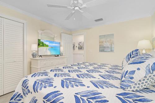 a bedroom with a blue and white bed and a television at 3rd Floor Sanibel Condo With Balcony And Beach Views 4B3 in Sanibel